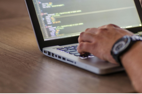 Mann sitzt an einem Laptop und programmiert | CLINARIS Geschichte