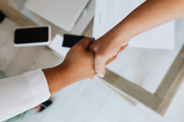 Handshake zwischen zwei Personen aus der Vogelperspektive | CLINARIS Geschichte